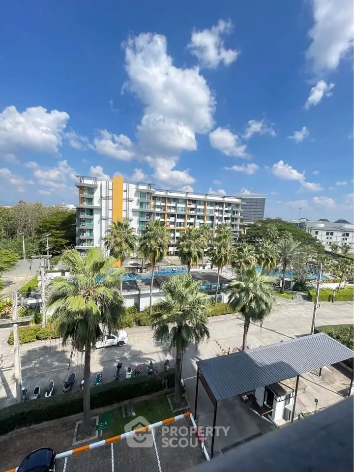 Stunning view of modern apartment complex with lush palm trees and clear blue sky.
