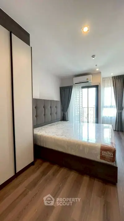 Modern bedroom with large window and stylish furnishings in a contemporary apartment.