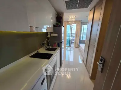 Modern kitchen with sleek appliances and open layout leading to a bright living area with city view.