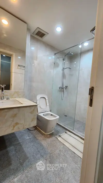 Modern bathroom with glass shower and marble sink in luxury apartment