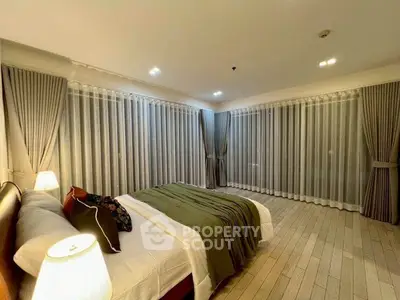 Spacious bedroom with elegant curtains and cozy lighting in modern apartment.