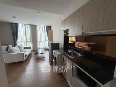 Modern open-layout living room with kitchen, featuring sleek design and large windows for natural light.