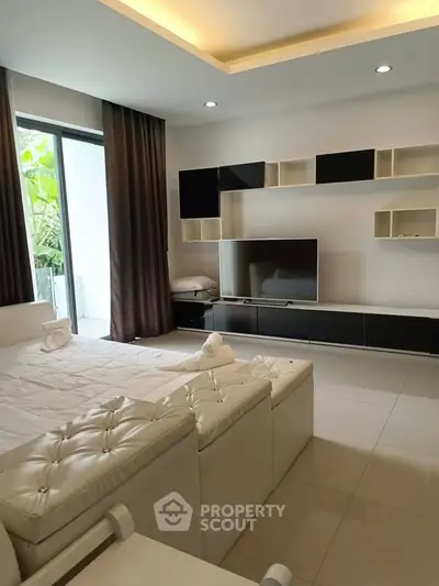 Modern living room with sleek furniture and large TV, featuring a bright and inviting atmosphere.