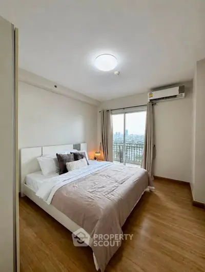Spacious bedroom with city view and modern decor in a high-rise apartment.