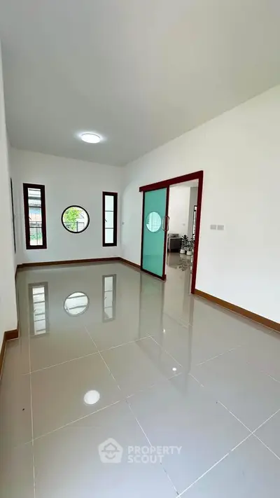 Spacious room with glossy tiled floors and unique circular window, perfect for modern living.