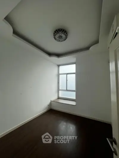 Bright and airy corner unit with gleaming hardwood floors and a large window inviting ample natural light, perfect for a cozy living space or a serene bedroom retreat.