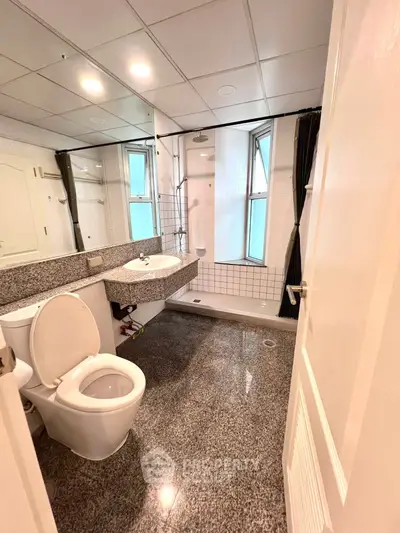 Modern bathroom with granite flooring and large mirror in a stylish apartment.