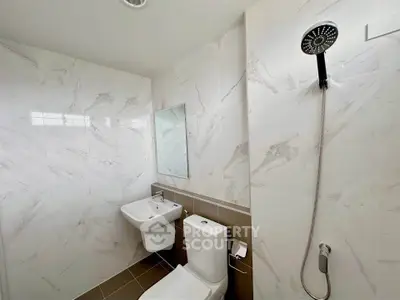 Modern bathroom with sleek fixtures and marble walls, featuring a shower and toilet.