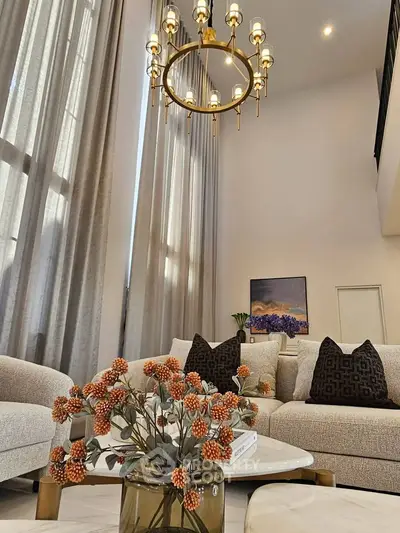 Luxurious living room with high ceilings, elegant chandelier, and stylish decor for a sophisticated ambiance.