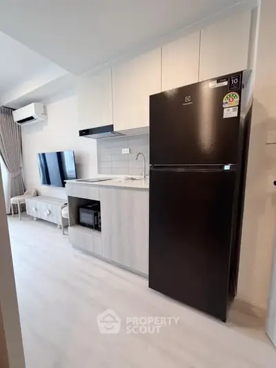 Modern kitchen with sleek black fridge and built-in microwave in stylish apartment.