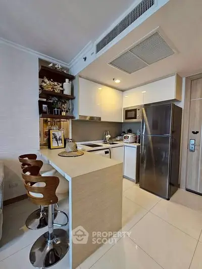 Modern kitchen with sleek appliances and stylish bar seating in a contemporary apartment.