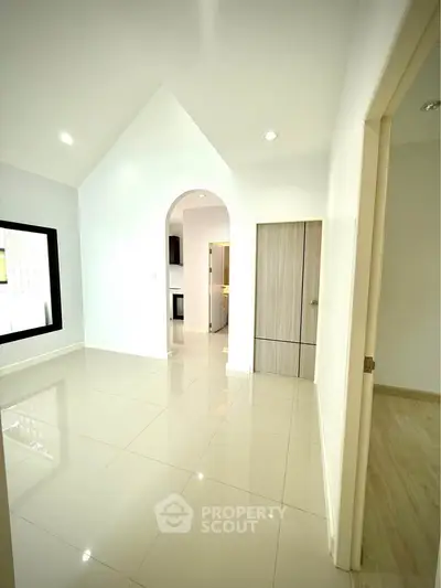 Spacious modern interior with high ceiling and sleek tile flooring, perfect for stylish living.