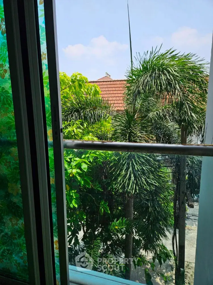 Scenic view from a window overlooking lush greenery and rooftops, perfect for nature lovers.