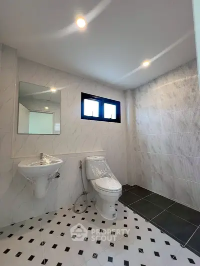 Modern bathroom with sleek design, featuring a toilet, sink, and stylish tile flooring.