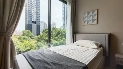 Modern bedroom with large window offering stunning cityscape and greenery views.