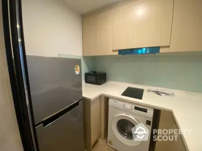 Modern compact kitchen with fridge, washing machine, and sleek cabinetry