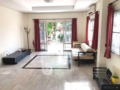 Spacious living room with large windows and garden view, featuring elegant marble flooring and modern furniture.