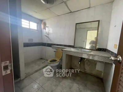 Spacious bathroom with tiled walls and large mirror, featuring a shower and toilet.