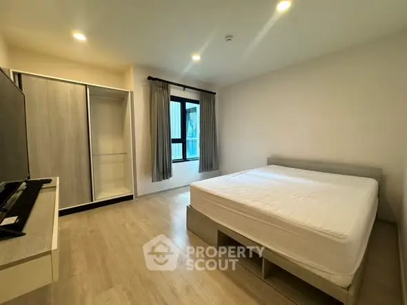 Spacious modern bedroom with large window and built-in wardrobe