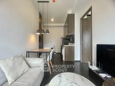 Modern living room with open kitchen, stylish furniture, and sleek appliances in a contemporary apartment.