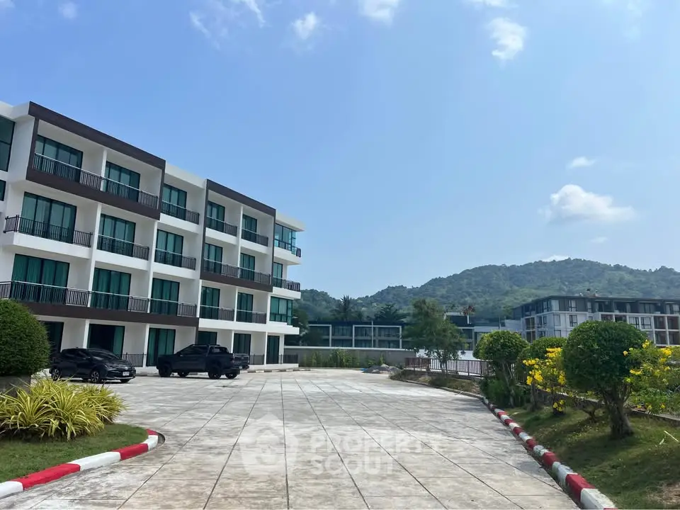 Modern apartment complex with mountain views and spacious parking area.