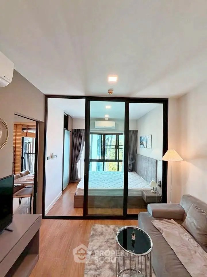 Modern apartment interior with glass partition, cozy living area, and stylish bedroom.