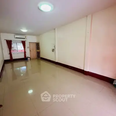 Spacious empty room with tiled flooring and natural light, ideal for customization.