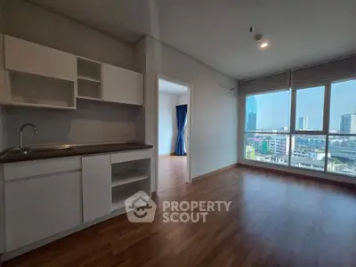Modern apartment with open kitchen and city view, featuring large windows and wooden flooring.
