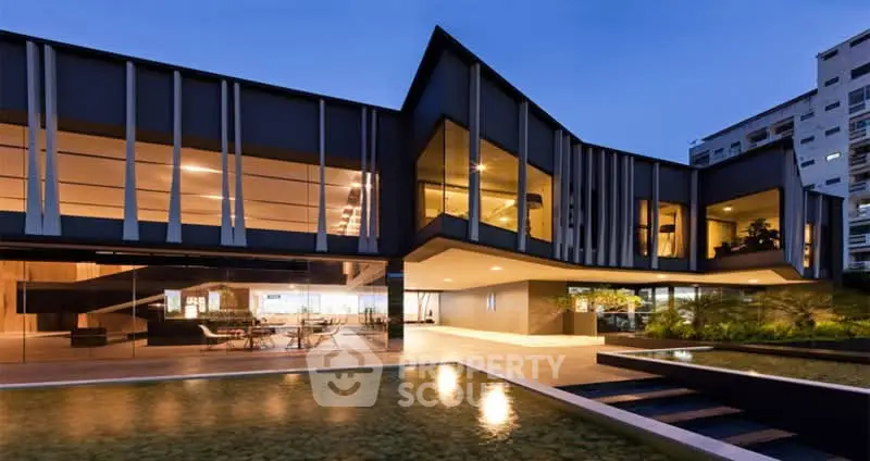 Stunning modern architectural home with expansive glass windows and serene water feature at dusk.