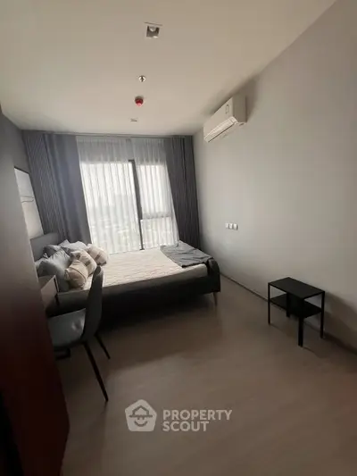 Modern bedroom with sleek design, featuring a comfortable bed, air conditioning, and natural light from large window.