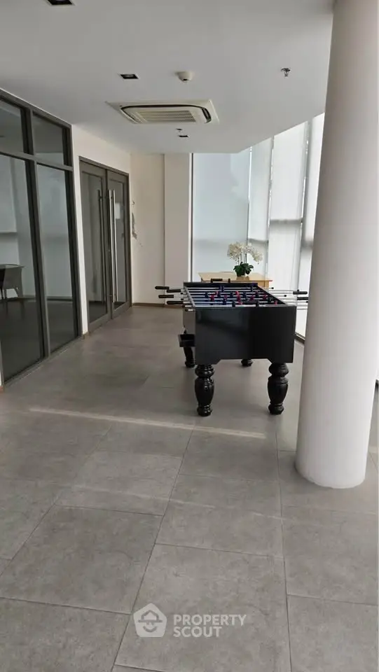 Modern common area with foosball table and glass walls in upscale building.