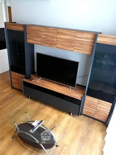 Modern living room with sleek TV stand and glass coffee table on wooden flooring.