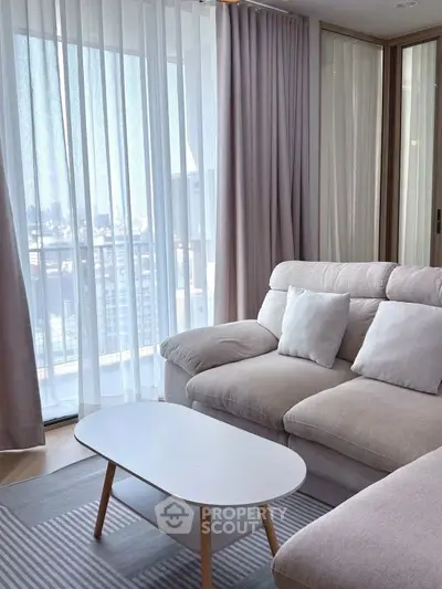 Modern living room with cozy beige sofa and city view from large windows.