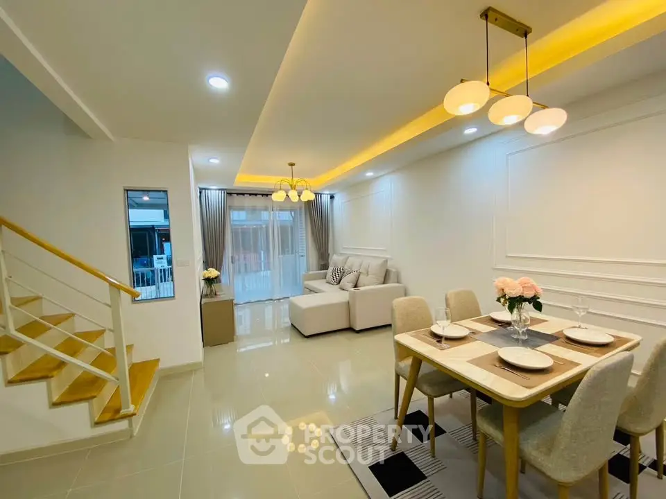 Modern open-plan living and dining area with elegant lighting and stylish decor.