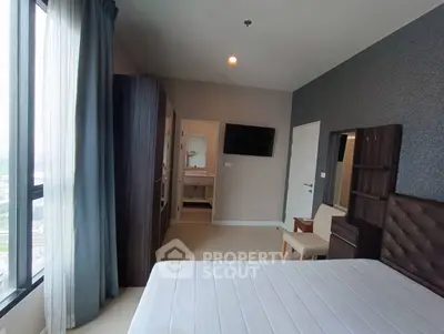 Modern bedroom with large window and city view, featuring stylish furniture and neutral tones.