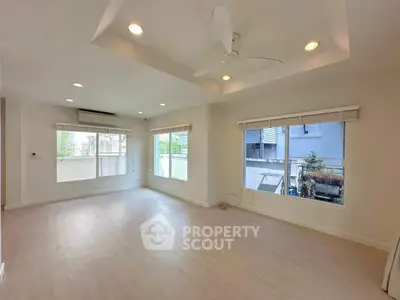 Spacious living room with large windows and ceiling fan in modern apartment