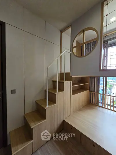 Modern loft-style bedroom with wooden stairs and large window view
