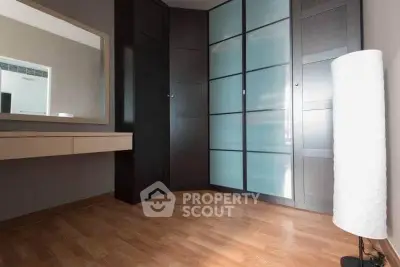Spacious modern bedroom with sleek wooden flooring and stylish wardrobe.
