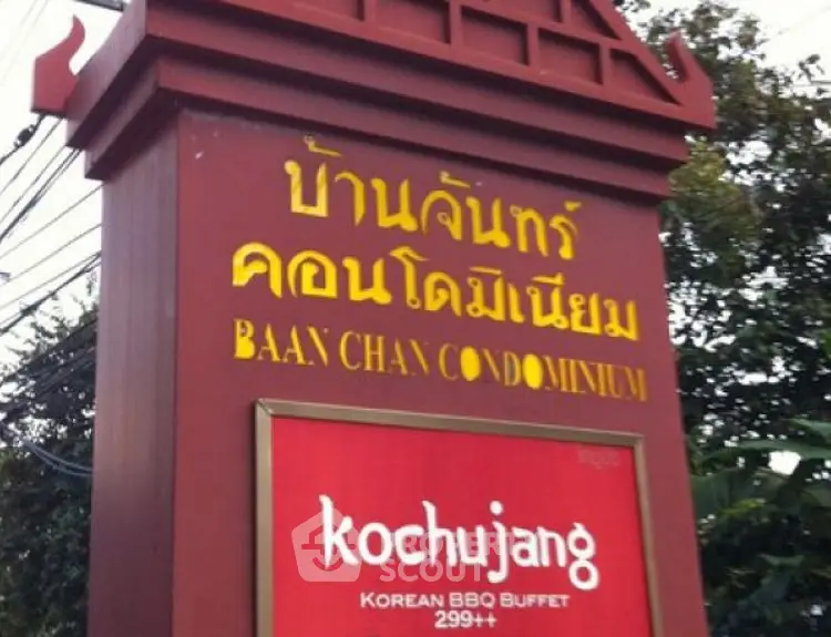 Entrance sign of Baan Chan Condominium with nearby Korean BBQ buffet advertisement.