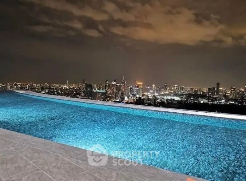 Stunning rooftop infinity pool with breathtaking city skyline view at night.