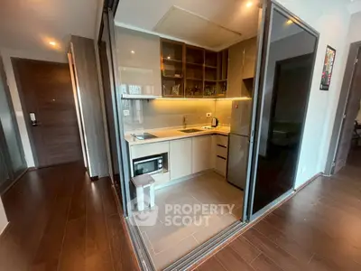 Modern compact kitchen with sleek design and glass partitions in a stylish apartment.