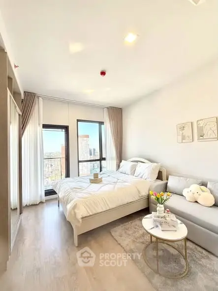 Bright and cozy bedroom with modern decor and city view, featuring a comfortable bed and stylish sofa.