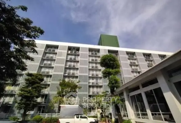 Modern multi-story building with contemporary facade and lush greenery in urban setting.