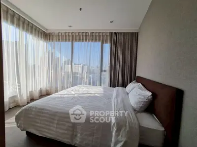 Spacious bedroom with city view and natural light, featuring modern decor and large windows.