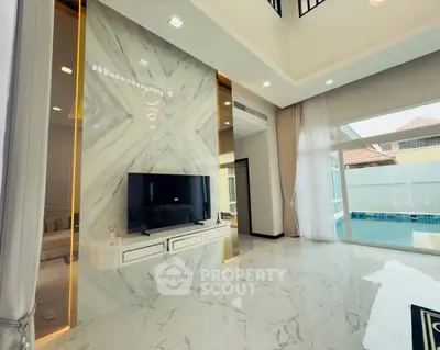 Luxurious living room with marble flooring and pool view, featuring modern TV setup and elegant decor.