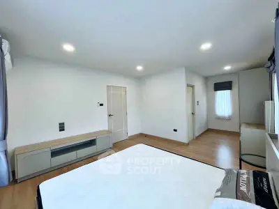 Spacious modern bedroom with wooden flooring and sleek furniture