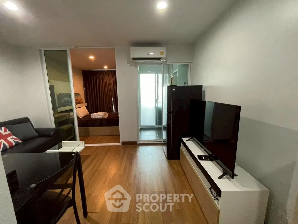 Modern living room with wooden flooring, sleek TV setup, and cozy seating area.