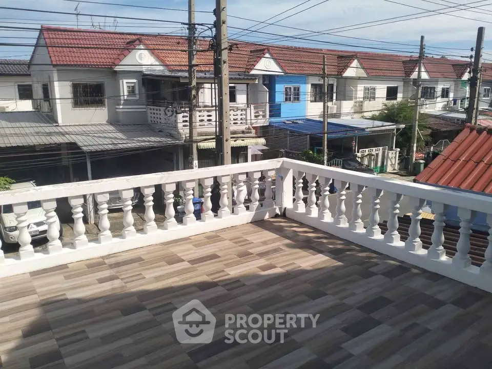 Spacious balcony with tiled flooring offering a view of charming townhouses in a serene neighborhood.