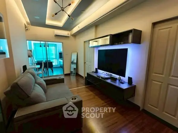 Modern living room with sleek design and ambient lighting, featuring a cozy sofa and large TV unit.