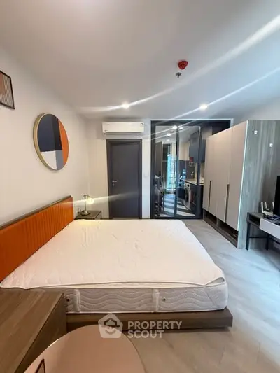 Modern bedroom with stylish decor and open layout leading to kitchen area.